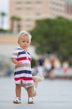 Tatlı toddler bebek çocuk, oyuncak ayı şehrin sakin bir akşam üzerinde oynamaya