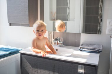 Bebek alarak banyo lavabo. Köpük ve sabun köpüğü ile pencere güneşli banyoda ile oynayan çocuk. Küçük çocuk banyo. Su eğlenceli çocuklar için. Hijyen ve cilt bakımı çocuk için. Banyo odası iç