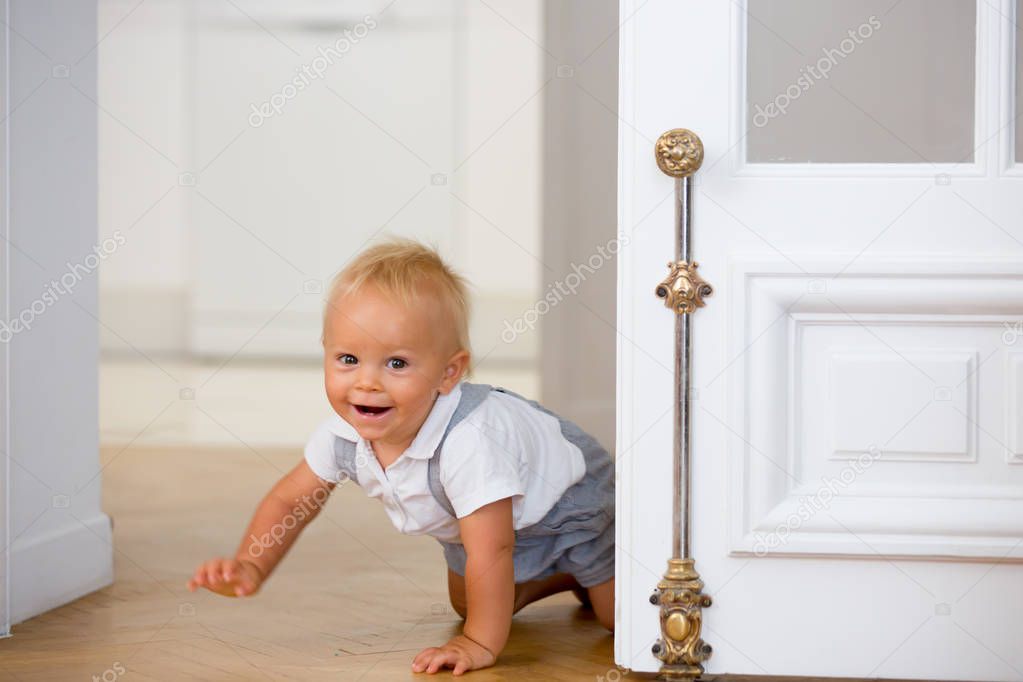 Little cute baby child, boy, crawling from behind a door at home