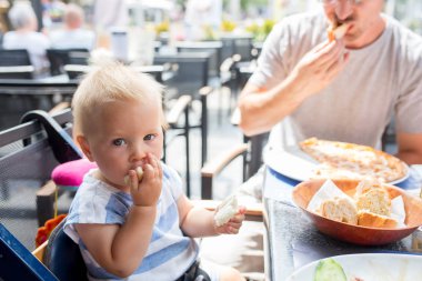 Tatlı bebek çocuk, çocuk restoranında sıcak yaz günü açık havada üzerinde ekmek yemek