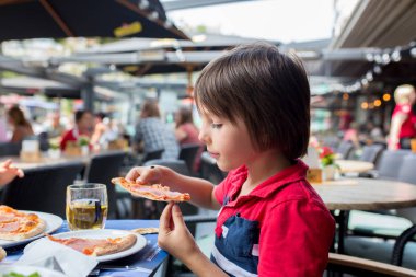 Sevimli çocuk, çocuk, pizza yemek restoranda, mutlu bir şekilde gülümseyerek ve ısırma