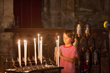 Küçük çocuk dua ediyor ve Ortodoks Kilisesi, iman ile üzgün çocuk bir mum koyar