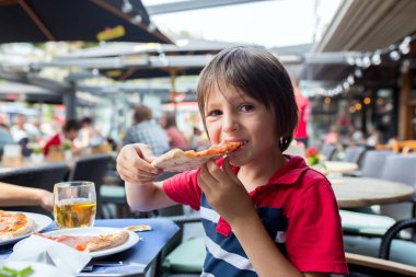 Sevimli çocuk, çocuk, pizza yemek restoranda, mutlu bir şekilde gülümseyerek ve ısırma