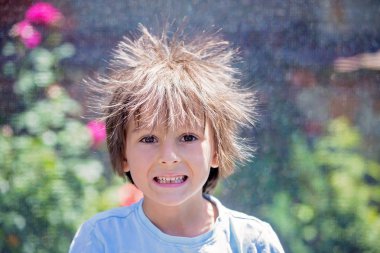 Statik elektrik saçı olan sevimli küçük bir çocuk. Trambolinde komik bir portresi çekiliyor.