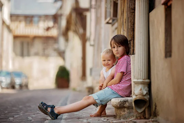 甘い男の子と彼の弟は ビンテージ スタイルの笑顔は幸せそのもの 町の古い部分の家の玄関に座って — ストック写真