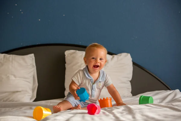 日当たりの良い部屋でカラフルなおもちゃでベッドで遊んでいる愛らしい赤ちゃん少年 甘い子 — ストック写真