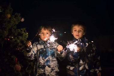 Okul öncesi çocuklar, maytap holding, açık havada yeni yıl arifesinde kutluyor, havai fişek izlerken