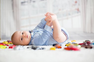 Bebek çocuk, yerdeki, oyuncak arabalar çevresindeki kameraya bakarak yalan yukarıdan öldürdü