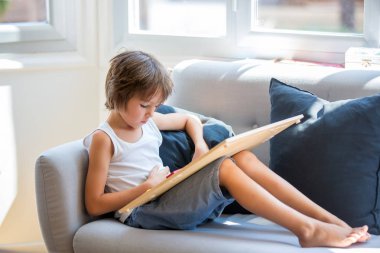 Prechool çocuk, bir kitap okumak, ahşap eğitici oyuncak ile oynayan