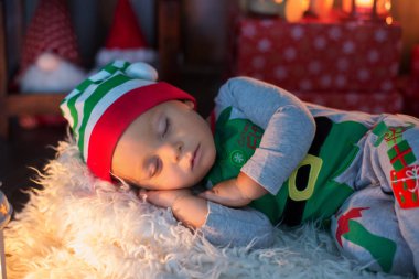 Tatlı yürümeye başlayan çocuk, çocuk, ile lots-in toys, Uyuyan bir elf, onun etrafında Noel dekorasyon gibi giyinmiş