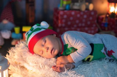 Tatlı yürümeye başlayan çocuk, çocuk, ile lots-in toys, Uyuyan bir elf, onun etrafında Noel dekorasyon gibi giyinmiş