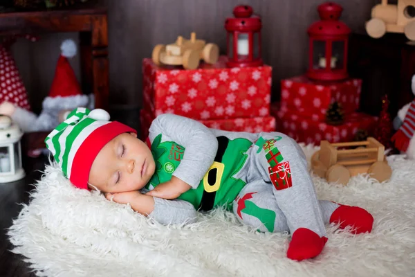 可爱的蹒跚学步的孩子 与许多玩具睡觉 穿着像一个精灵 Cristmas 装饰他周围 — 图库照片