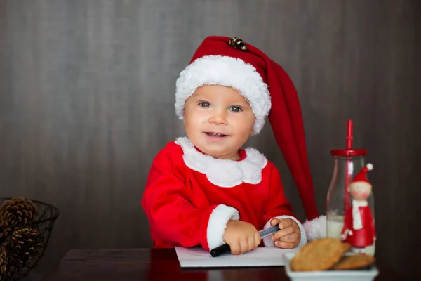 甘い幼児の子 男の子 クッキーを食べたり牛乳を飲む家庭では サンタさんへ手紙を書く — ストック写真