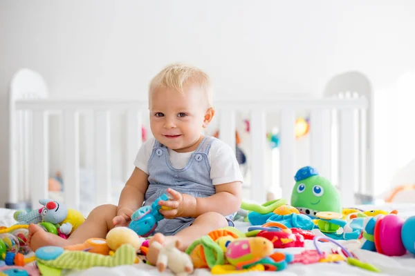 笑顔は幸せそのものを日当たりの良い寝室の多くのカラフルなおもちゃで遊んで 赤ちゃん幼児少年 — ストック写真