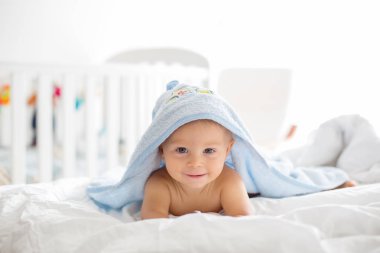Küçük şirin bebek çocuk, banyo, güneşli yatak odası, beyaz sayfaları sonra havlu ile yatakta yalan
