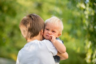 Küçük toddler bebek çocuk, onu parkta, taşıyan ağlayan, büyük kardeş bebeğim kameraya bakıyor