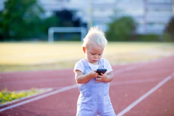可爱的男婴在公园里玩手机 数字技术在孩子手里 带智能手机的幼儿画像 — 图库照片
