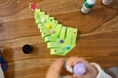 Üstten görünüm çocuğun, kardan adam ve kış ağaç yapıyor. Makas, yapıştırıcı, kalem, işaretleri, kağıt sayfalarının ve hurda ahşap arka plan üzerinde. Eğlenceli çocuk kış arka plan