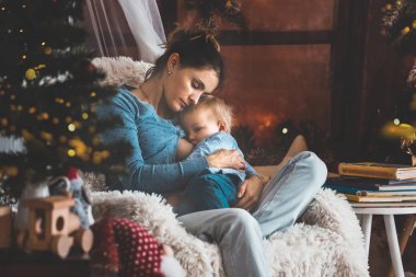 Yürümeye başlayan çocuk oğlu rahat koltuk Noel ağacı, yakın oturan anne emzirme kış