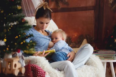 Yürümeye başlayan çocuk oğlu rahat koltuk Noel ağacı, yakın oturan anne emzirme kış