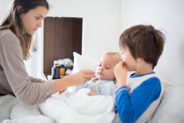 Anne ve bebek pijama, sabahın erken saatlerinde, onun hasta yürümeye başlayan çocuk bakımı anne. Ateş ve çalışan burun ile yatakta bebek
