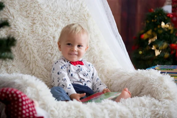 Roztomilý Chlapec Čtení Knihy Sedí Židli Pod Vánoční Stromeček Doma — Stock fotografie