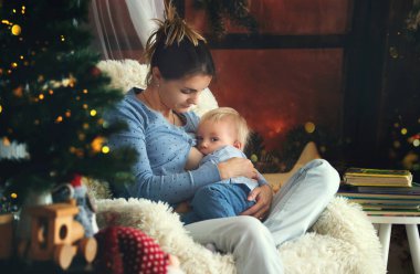 Yürümeye başlayan çocuk oğlu rahat koltuk Noel ağacı, yakın oturan anne emzirme kış
