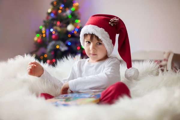Χαριτωμένο Αξιολάτρευτο Αγόρι Διαβάζει Ένα Βιβλίο Μπροστά Από Χριστουγεννιάτικο Δέντρο — Φωτογραφία Αρχείου
