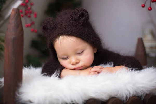 クリスマスの装飾テント 木製のベッドで眠っている手作り編みクマの衣装でかわいい幼児男の子 — ストック写真