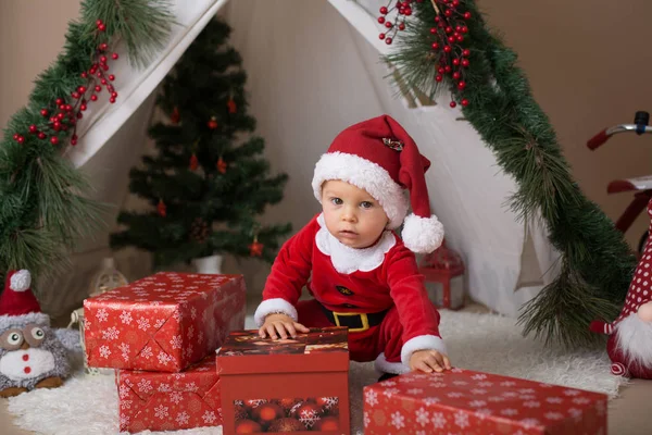 可爱的幼儿男婴身着圣诞老人服装 在家里玩装饰圣诞节的茶杯前 — 图库照片