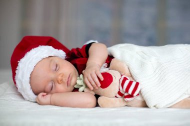 Tutmak oyuncak Santa şapka ve kot giyen küçük uyku yeni doğan oğlu,