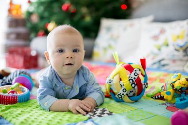 Mutlu üç aylık bebek çocuk, evde bir renkli etkinlik battaniye, oyuncaklar ve onun etrafında farklı etkinlik oynamak