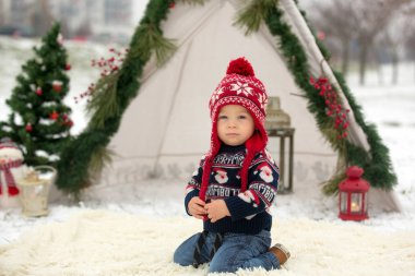 Çocuklu mutlu bir aile, Noel 'de dışarıda karda eğleniyorlar, kızakla oynuyorlar, çadırı kuruyorlar ve Noel süslemeleriyle oynuyorlar.