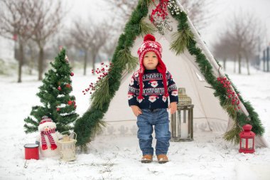 Çocuklu mutlu bir aile, Noel 'de dışarıda karda eğleniyorlar, kızakla oynuyorlar, çadırı kuruyorlar ve Noel süslemeleriyle oynuyorlar.
