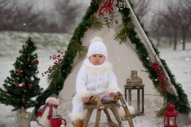 Çocuklu mutlu bir aile, Noel 'de dışarıda karda eğleniyorlar, kızakla oynuyorlar, çadırı kuruyorlar ve Noel süslemeleriyle oynuyorlar.