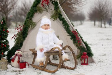Çocuklu mutlu bir aile, Noel 'de dışarıda karda eğleniyorlar, kızakla oynuyorlar, çadırı kuruyorlar ve Noel süslemeleriyle oynuyorlar.