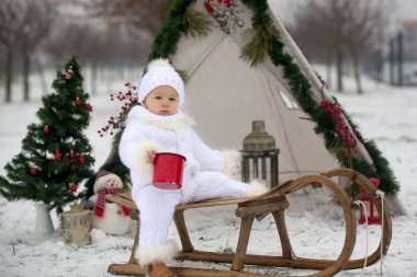 Çocuklu mutlu bir aile, Noel 'de dışarıda karda eğleniyorlar, kızakla oynuyorlar, çadırı kuruyorlar ve Noel süslemeleriyle oynuyorlar.