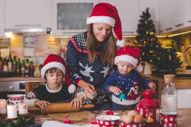 Tatlı çocuk ve ağabeyi, çocuklar, annenize mutfakta Noel kurabiyeleri hazırlarken yardım ediyorlar.
