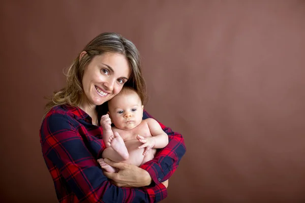 若い母親 彼女の生まれたばかりの赤ちゃんの男の子を Caressing 彼女の腕の中で抱っこと幸福から笑顔 — ストック写真