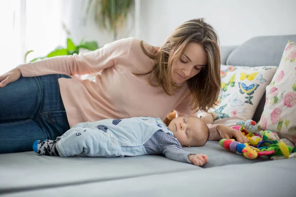 かわいい赤ちゃんの少年と彼の母親は リビング ルーム おもちゃで遊んで 早期幼児開発のための活動のソファに横になっています — ストック写真