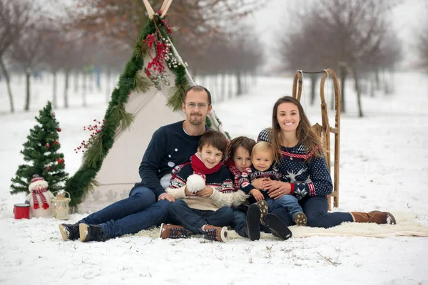 雪の中で楽しい屋外クリスマスを過ごし ティーピー クリスマスの装飾で遊んでいる子供たちと幸せな家族 — ストック写真