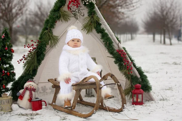 Çocuklu mutlu bir aile, Noel 'de dışarıda karda eğleniyorlar, kızakla oynuyorlar, çadırı kuruyorlar ve Noel süslemeleriyle oynuyorlar.