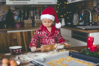 Tatlı çocuk ve ağabeyi, çocuklar, annenize mutfakta Noel kurabiyeleri hazırlarken yardım ediyorlar.