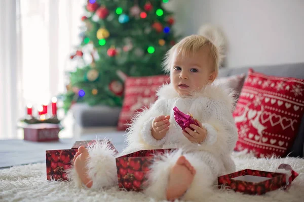 好奇的小男孩 一身毛绒绒的白衣 躺在沙发上玩着礼物 开心地笑着 — 图库照片