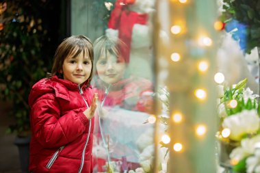 Güzel küçük çocuk, çocuk, Noel dekorasyon oyuncak Dükkanı Vitrini ile izlerken, bir hediye isteyen, onun yansıması penceresinde