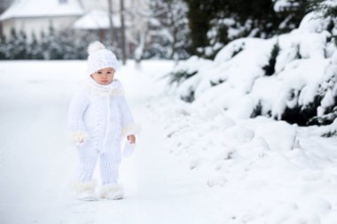 Tatlı küçük çocuk, kış günü dışarıda karla oynuyor, kar yağıyor.