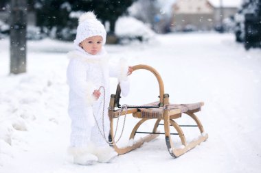 Tatlı küçük çocuk, kış günü dışarıda karla oynuyor, kar yağıyor.