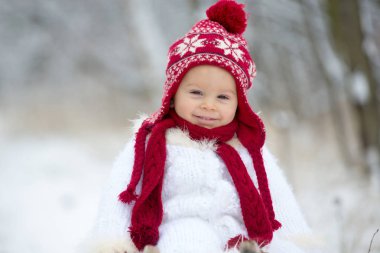 Sevimli küçük yürümeye başlayan çocuk ve açık havada bir kış gününde kar ile oynarken, kar yağışı büyük kardeşleri
