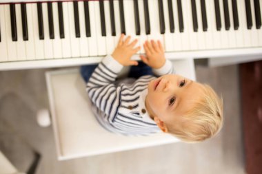 Tatlı olumlu yürümeye başlayan çocuk piyano. Küçük çocuklar, çocuk okulda müzik aletleri öğrenme için erken müzik eğitimi