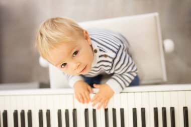 Tatlı olumlu yürümeye başlayan çocuk piyano. Küçük çocuklar, çocuk okulda müzik aletleri öğrenme için erken müzik eğitimi
